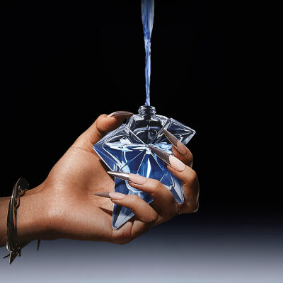 un flacon de parfum bleu angel qui est rempli par une recharge tenue dans une main