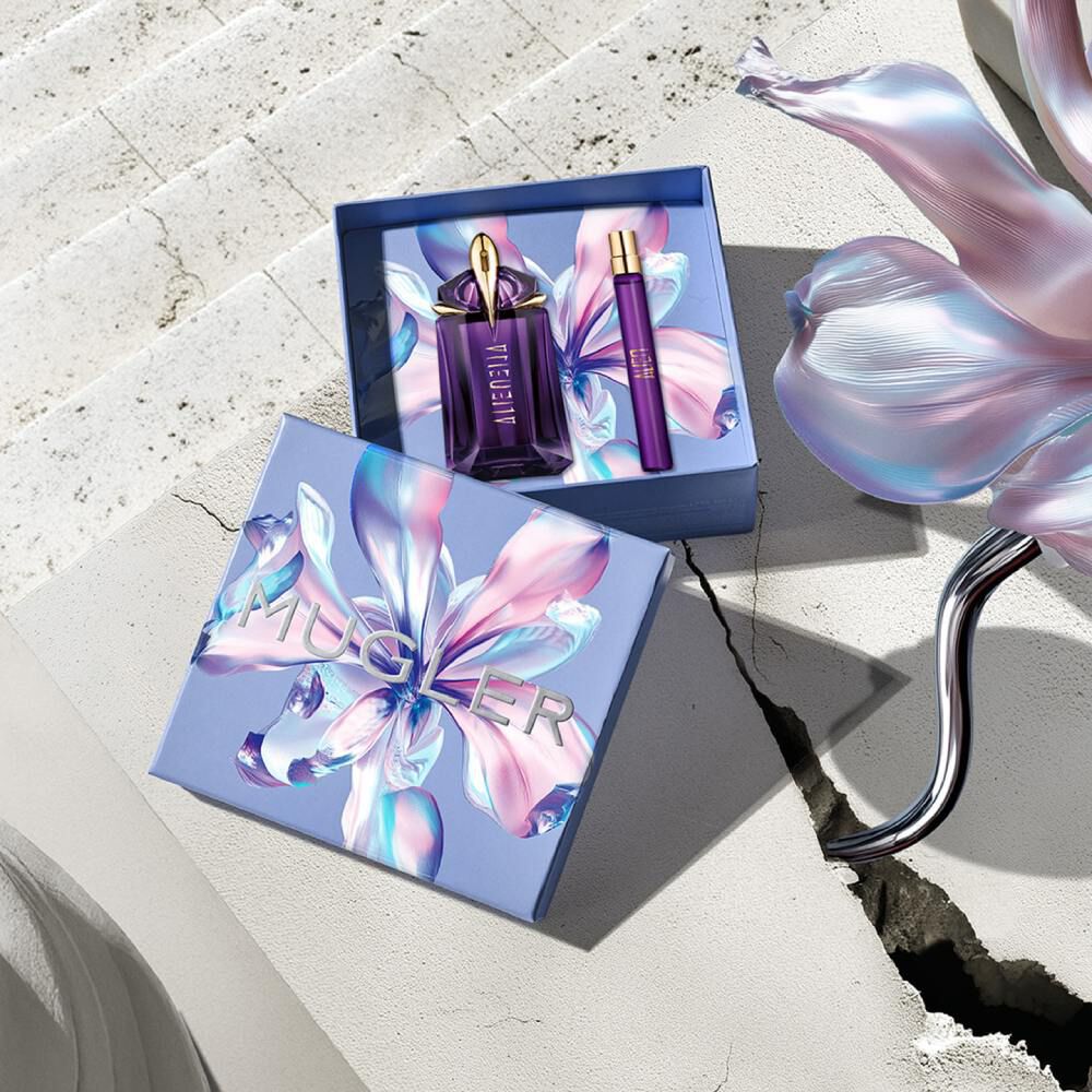 La boite cadeau de la fete des meres 2026 de Mugler s’est ouverte pour reveler le duo Alien Eau de Parfum 60 ml et spray de voyage, presente sur une surface en pierre eclairee par le soleil.