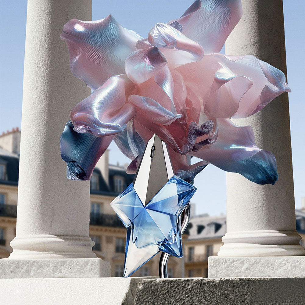 Le talisman bleu en etoile bleue Angel Eau de Parfum se dresse sur une corniche de pierre parisienne, encadre de sculptures florales irisees et de piliers blancs classiques.