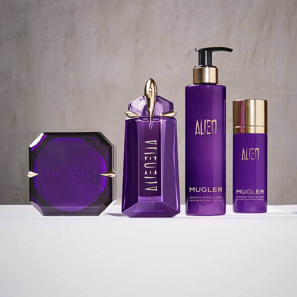 un flacon de parfum violet et trois produits de soins de la peau violet sur un fond beige