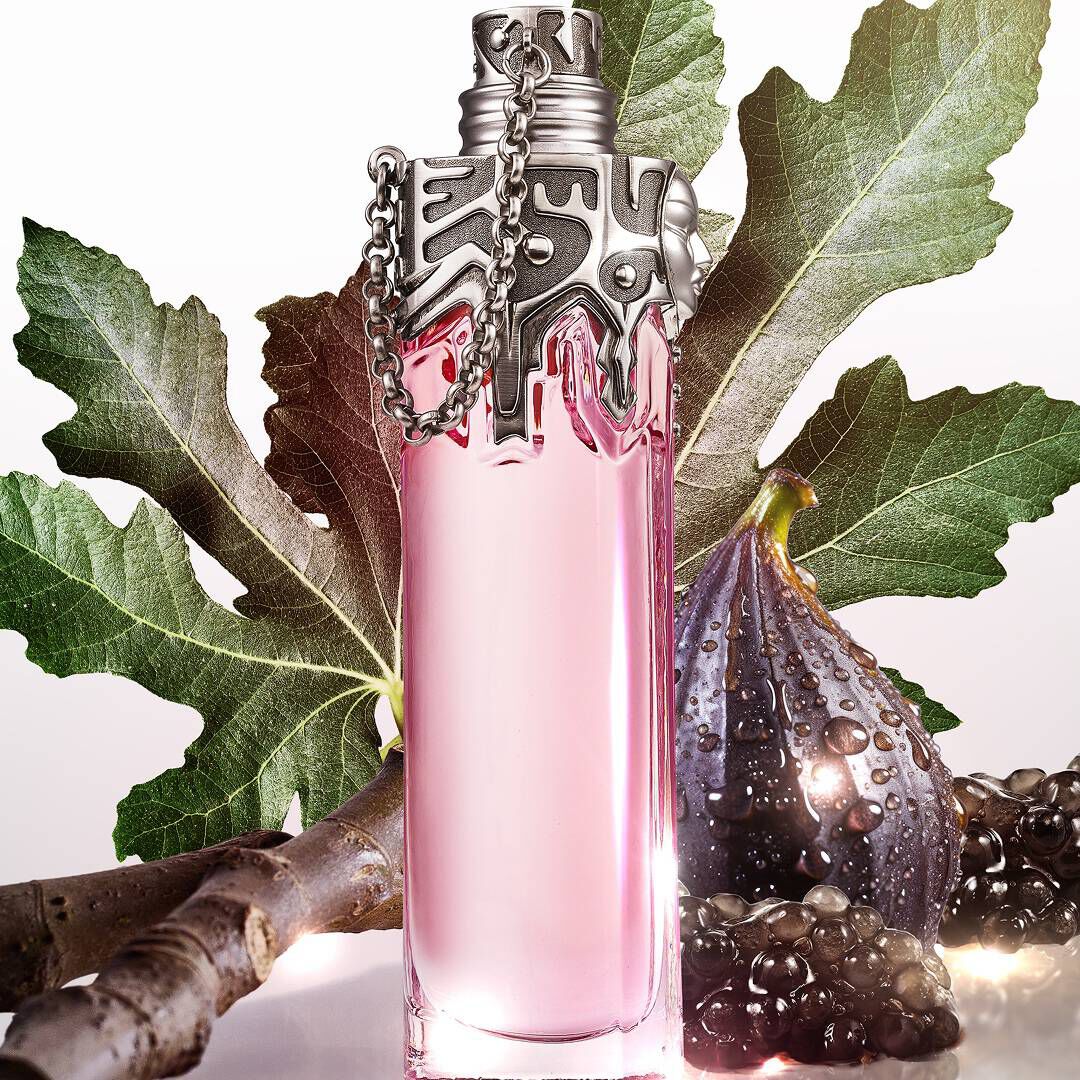 un flacon de parfum rose pale entoure de figues et de feuilles vertes