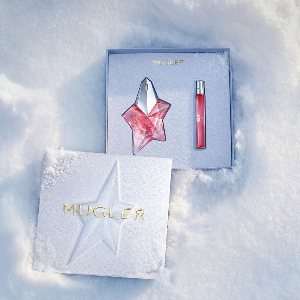 Un coffret cadeau Mugler ouvert, texture et bleu glace luisant reposant sur la neige, revelant un coffret d’eau de parfum angel nova 50 ml