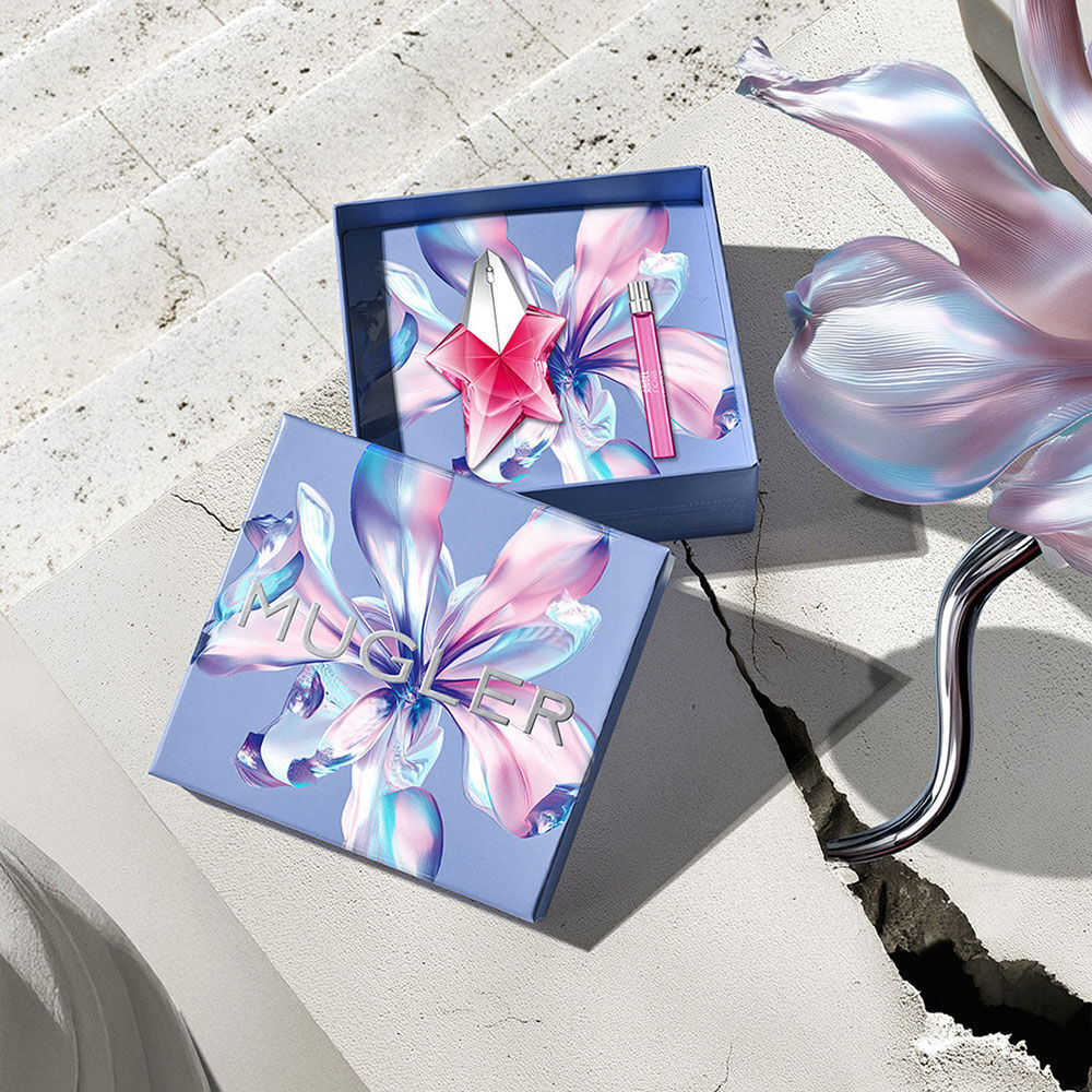 Boite cadeau de la fete des meres Mugler avec un motif floral kaleidoscopique, ouverte pour reveler l’etoile Angel Nova Eau de Parfum sertie sur un fond de pierre baigne de soleil.