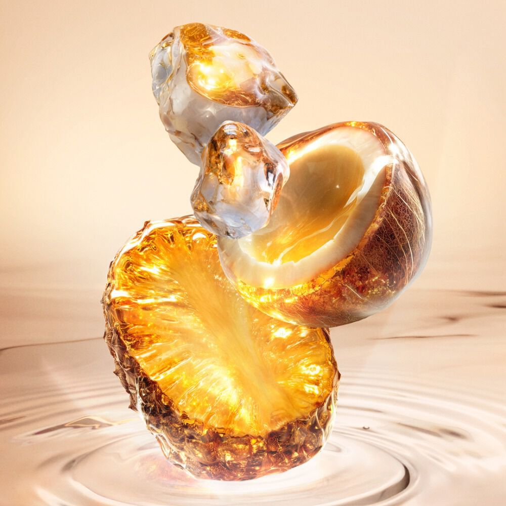 Nature morte Starlicious Pineapple Musk nouvelle avec la fine bouteille en verre entouree de ses ingredients cles : une tranche d’ananas lumineuse, une coquille de noix de coco cassee et un musc cristallin, le tout sur un fond d’eau chaud, lumineux et ondulant.