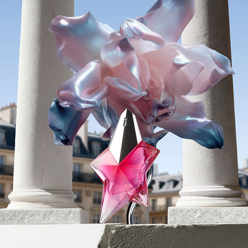 La bouteille Angel Nova etoile rose se dresse sur un balcon de pierre parisienne, encadree de fleurs irisees surrealistes et de piliers blancs classiques.