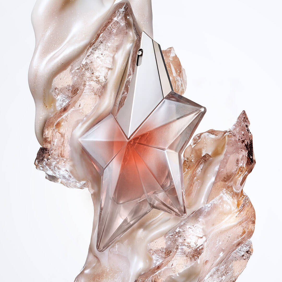 un flacon de parfum rose en forme d'etoile entoure d'un morceau de bois, de musc et de lait d'amande