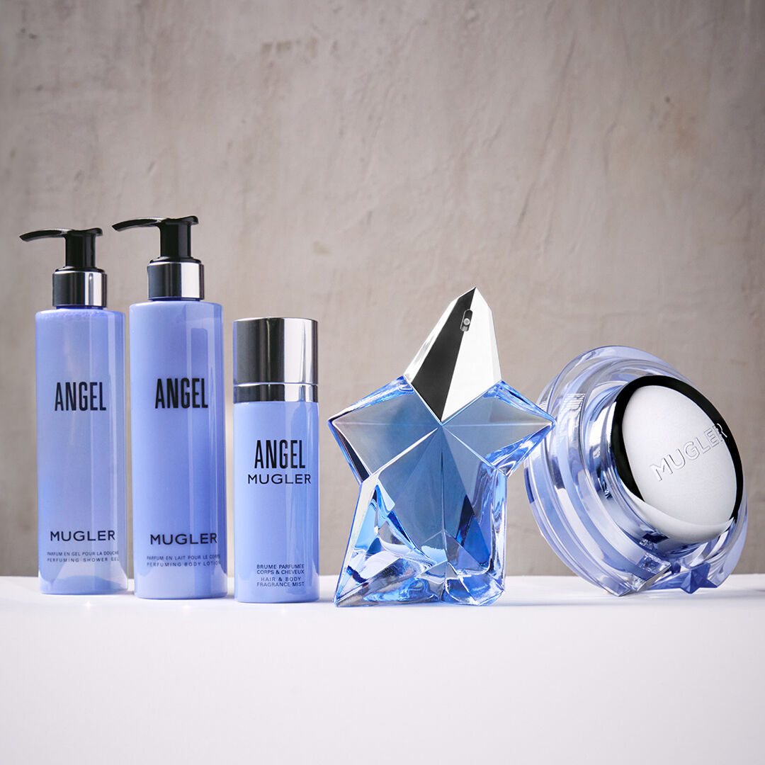 cinq produits de soin de la peau aux flacons bleus mugler poses sur un fond marbre