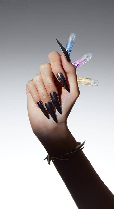 Main feminine avec des ongles longs et pointus tenant plusieurs flacons a goutte.