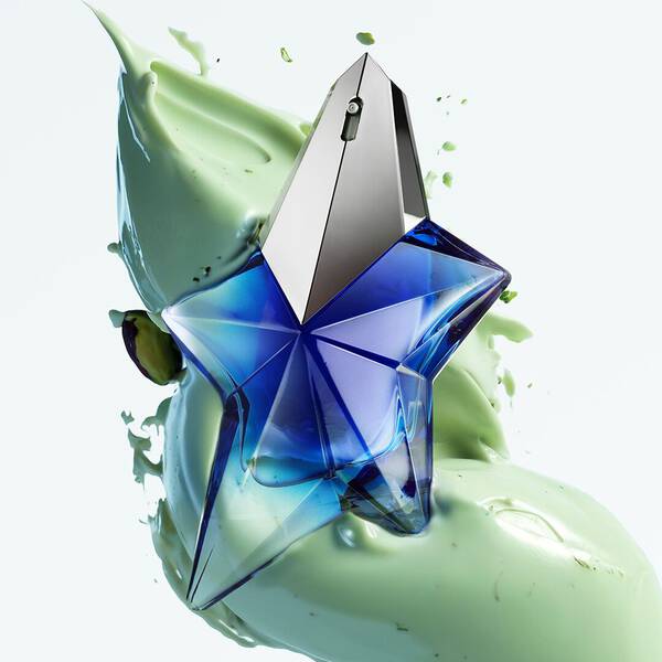 flacon de parfum bleu angel stellar mugler avec de la pistache liquide en fond