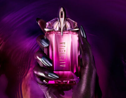 un flacon de parfum rose alien entoure de framboises et une femme a la peau noire