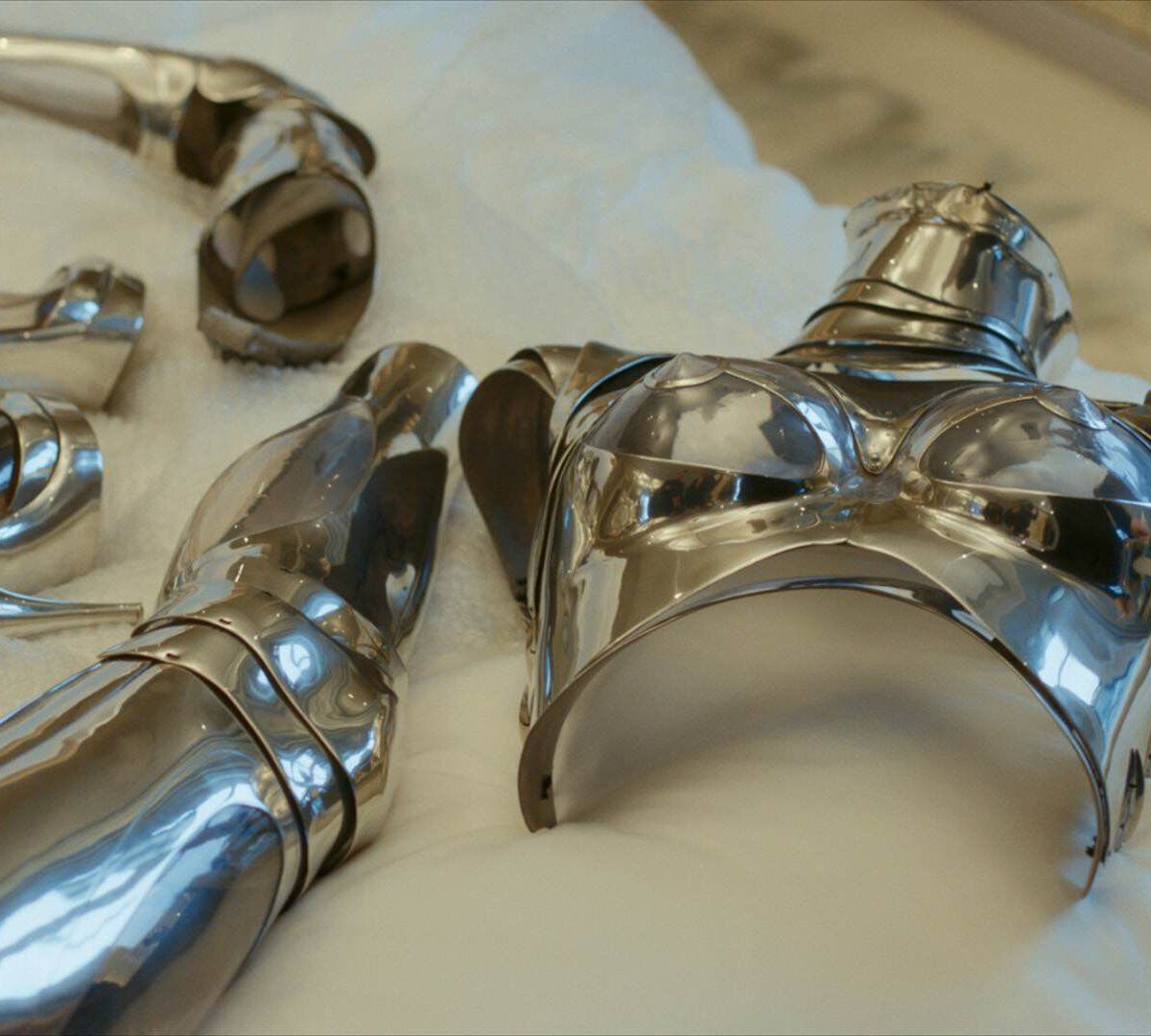 une armure argentee de femme pose sur un drap blanc