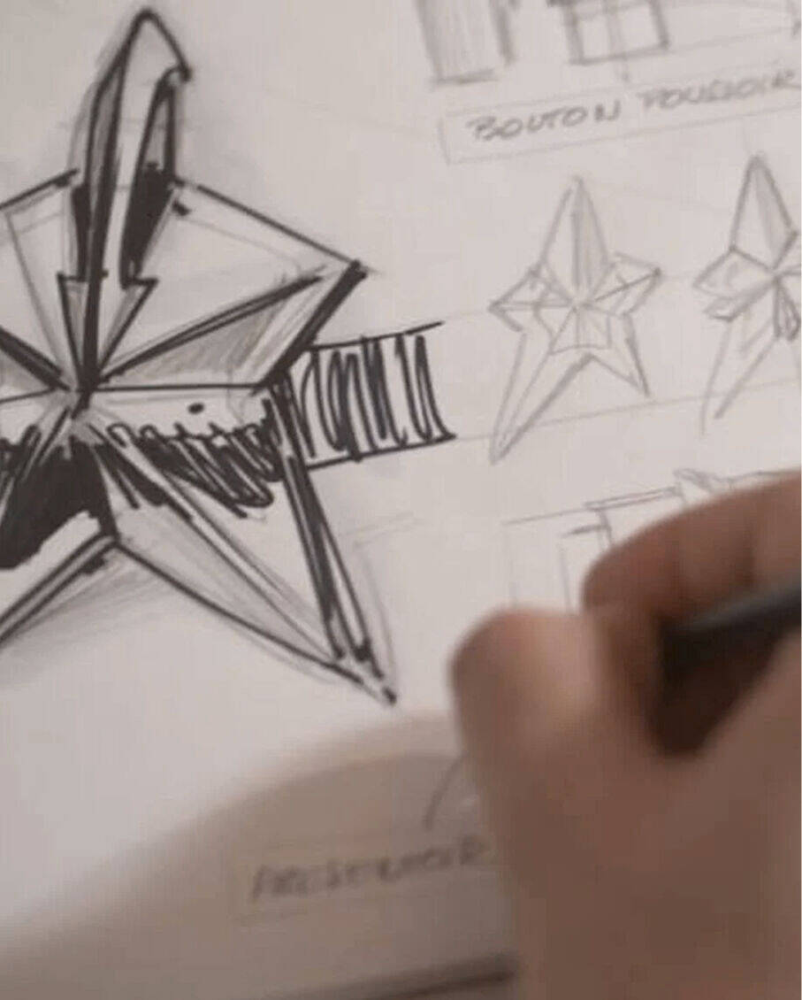Les mains d'un createur esquissant le motif architectural en forme d'etoile d'un flacon de parfum Mugler.