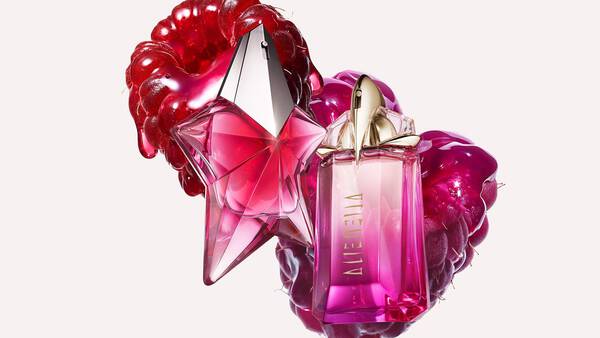 deux flacons de parfums rose mugler devant deux framboises sur un fond clair