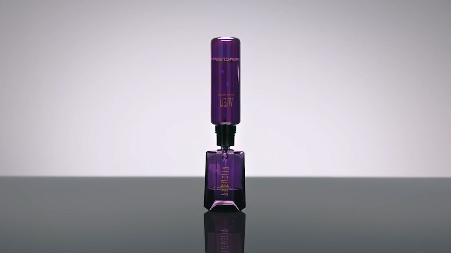 Flacon de parfum violet elegant sur une surface reflechissante.