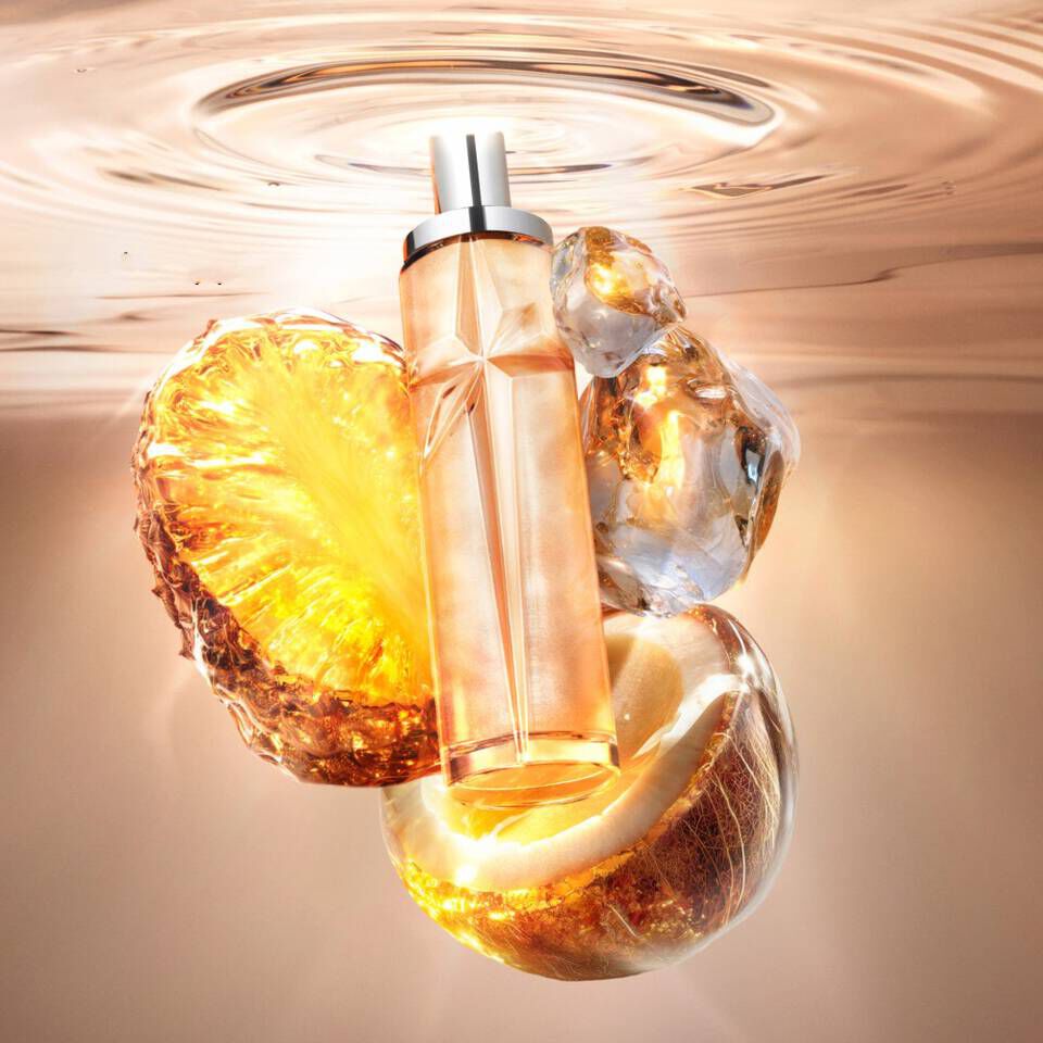 Un flacon de parfum orange en forme d'etoile flottant dans l'eau, avec des ananas et des noix de coco