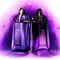 Deux flacons de parfum Alien de couleur violette, avec un design elegant et moderne, se detachent sur un fond violet lumineux.