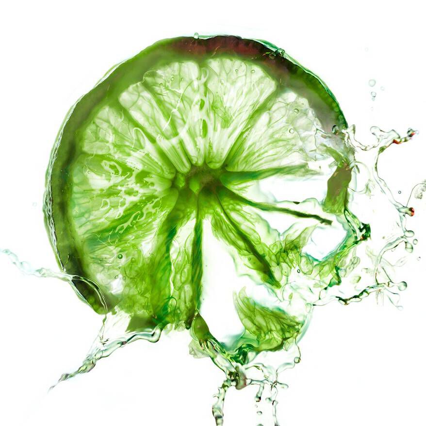 Tranche de lime verte avec des gouttes d'eau, sur fond lumineux.