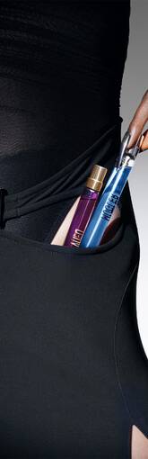 Une main feminine tient des flacons de parfum dans la poche d'une robe noire, mettant en avant l'elegance et le style.