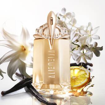 Flacon de parfum elegant avec des fleurs blanches, des gousses de vanille et une tranche de citron en arriere-plan.