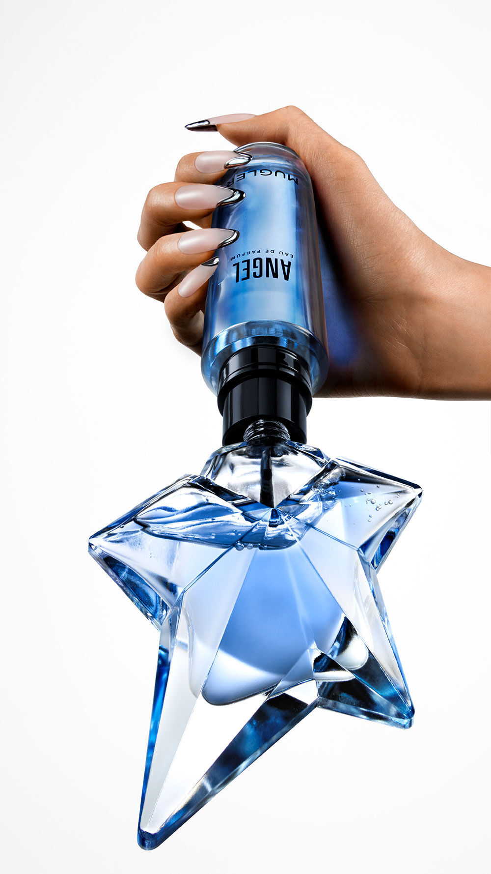 un flacon de parfum bleu angel qui est rempli par une recharge tenue dans une main