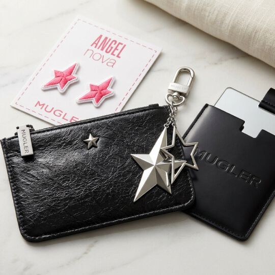 un miroir de poche noir, un porte-monnaie noir, un porte cles etoile argente sur un fond marbre.