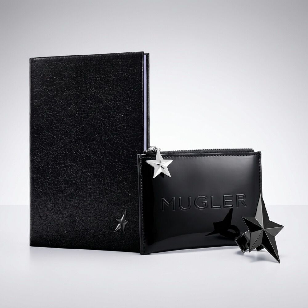 un bloc note noir, une trousse noir mugler et une etoile noir sur un fond gris clair