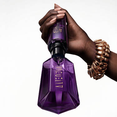 un flacon de parfum violet alien avec une main qui tient un flacon recharge