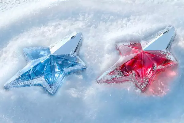 deux flacons de parfums rose mugler devant deux framboises sur un fond clair