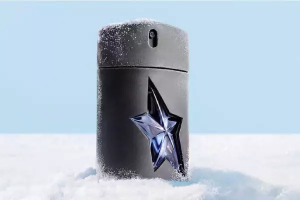 Un flacon noir et epure de l'eau de toilette masculine Mugler AMen, orne de son emblematique etoile bleue decoupee, se dressant au milieu d'une douce congere.