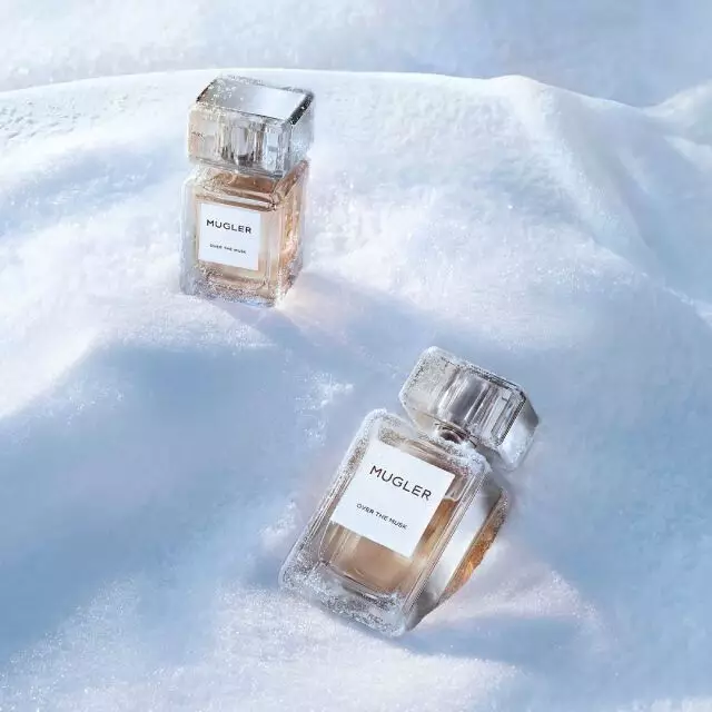 Deux flacons de parfum Mugler « Les Exceptions », elegants et rectangulaires, en verre epais, remplis d'un liquide dore, disposes en diagonale dans un paysage enneige. Le texte indique « cadeaux de luxe ».