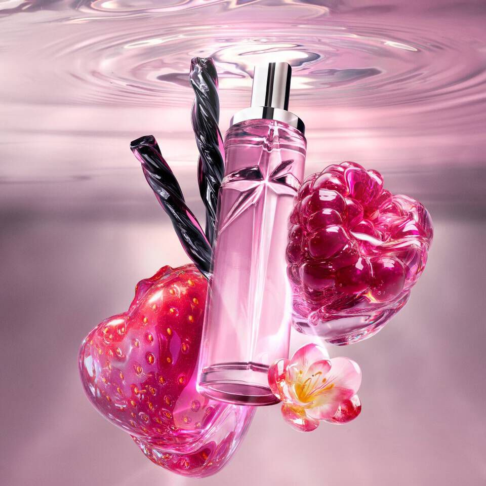 Un flacon de parfum orange en forme d'etoile flottant dans l'eau, avec des ananas et des noix de coco