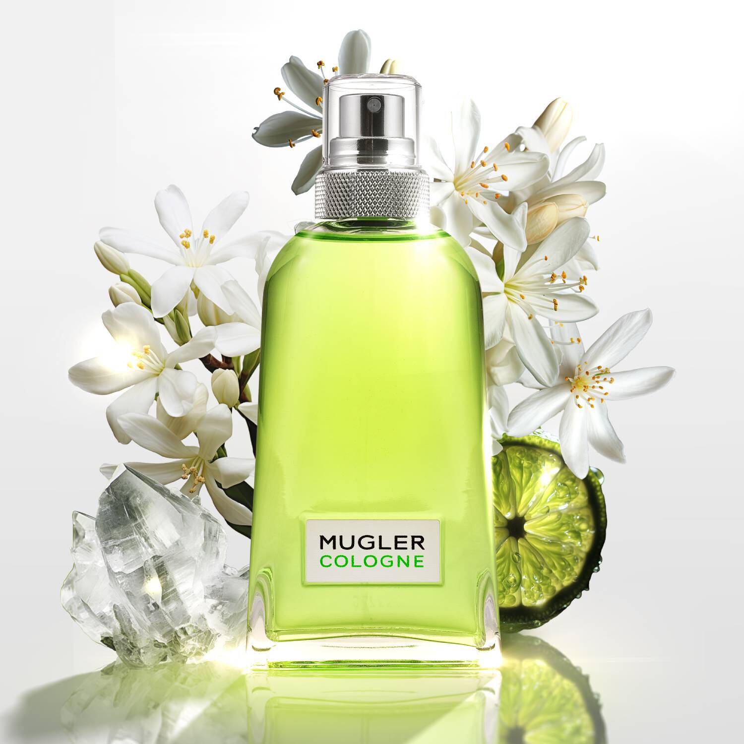 Flacon de parfum Mugler Cologne entoure de fleurs blanches et de tranches de citron vert, avec des glacons en arriere-plan.