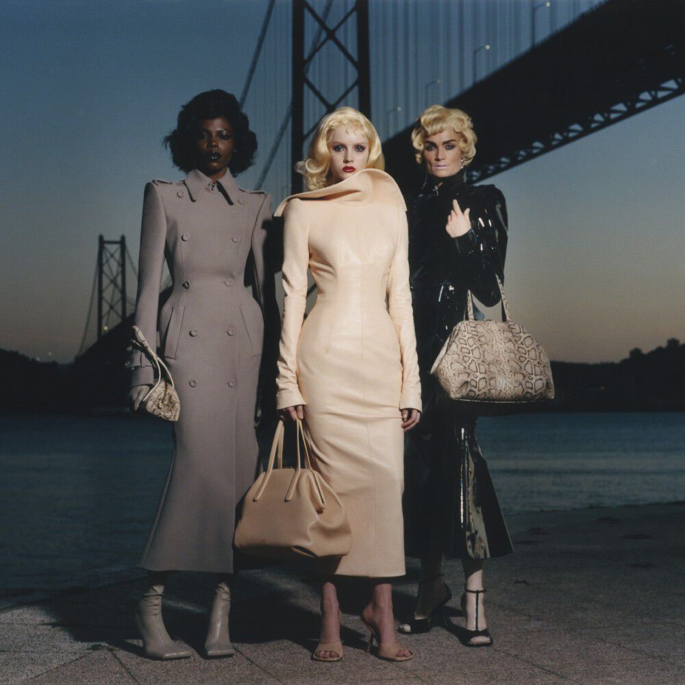 Trois mannequins posent vetues de tenues Mugler sous un pont, dans un decor typiquement new-yorkais