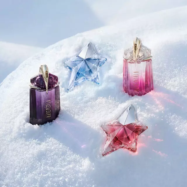 Un flacon violet d'Alien de Mugler, un flacon bleu clair d'Angel, un flacon rose d'Alien et un flacon rose d'Angel, magnifiquement disposes sur une surface de neige douce et ondulante. Le texte indique : « L'heure glacee est arrivee. Plongez dans un paysage givre et decouvrez des cadeaux qui marquent les esprits. Des tresors givres pour vos proches ou pour vous-meme, qui incarnent une opulence scintillante. Faites vos achats avant que la glace ne fonde. »
