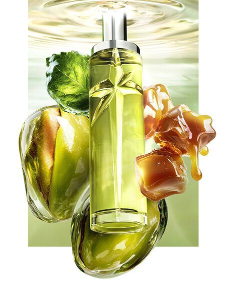 Nouvelle image de nature morte pour Starlicious Pistachio Praline, mettant en scene le flacon elance entoure de ses ingredients phares : une feuille de patchouli, des pistaches entieres et des cubes de caramel fondants, le tout sur fond d'eau ondulante d'un vert lumineux.