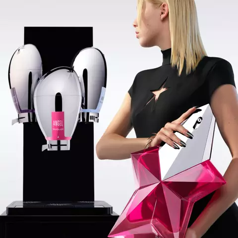 Une photographie de trois distributeurs de parfum metalliques reflechissants, l'un avec une etiquette rose, l'autre avec une etiquette bleue et le dernier avec une etiquette violette, sur un fond sombre.