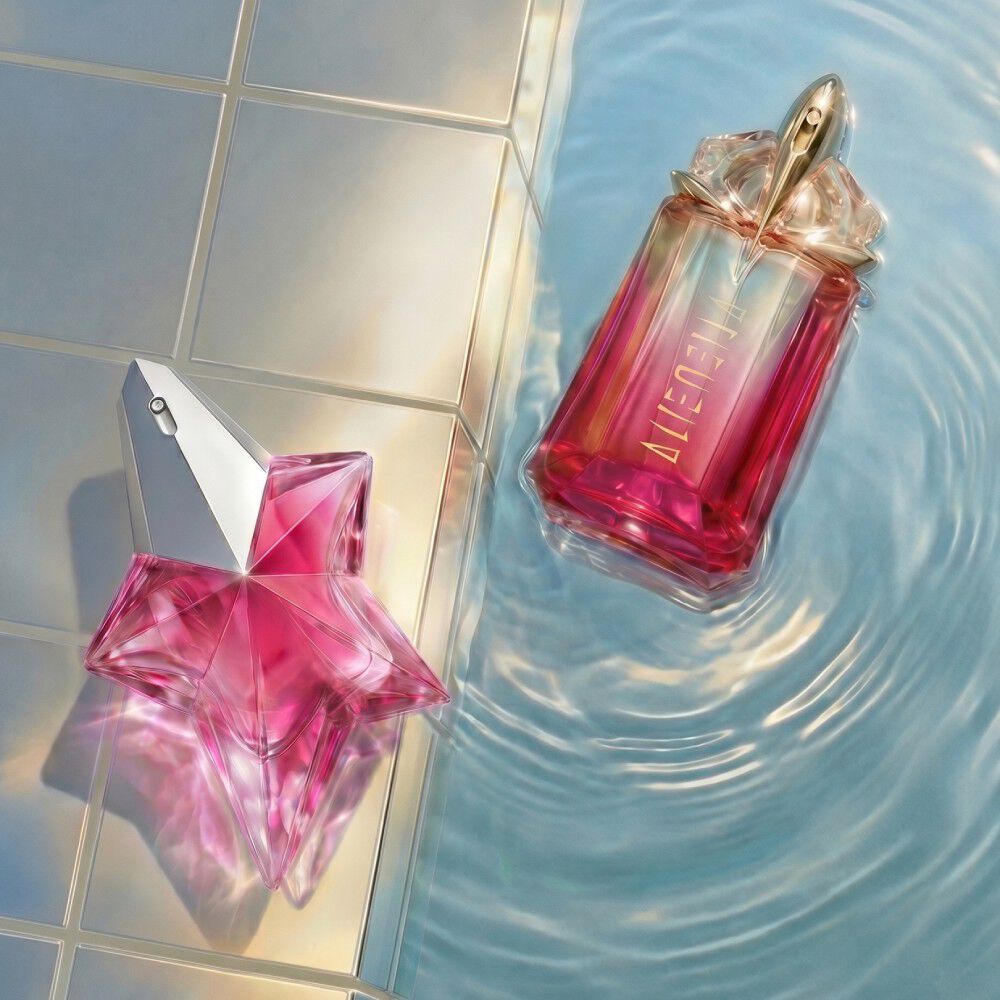 un flacon de parfum rose en forme d'etoile avec a cote un autre parfum rouge poses sur un fond piscine