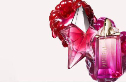 deux flacons de parfums rose mugler devant deux framboises sur un fond clair