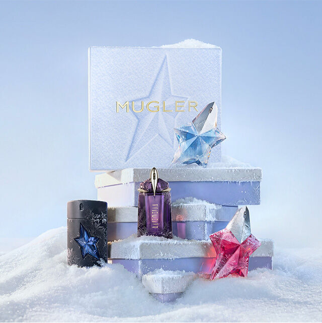 Une pile de trois coffrets cadeaux Mugler bleu clair poses sur la neige, entoures d'un flacon noir d'eau de toilette A*Men, d'un flacon violet d'eau de parfum Alien, d'un flacon bleu d'eau de parfum Angel et d'un flacon rose d'eau de parfum Angel, dans un paysage enneige. Le texte indique : « Le Black Friday approche a grands pas ».