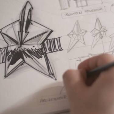 une main tenant un crayon qui dessine une etoile sur une page blanche