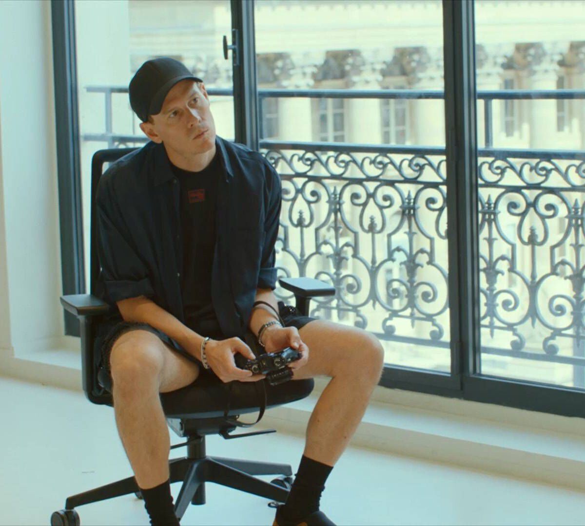 un homme assis sur une chaise qui tient un appareil photo dans ses mains et tourne la tete