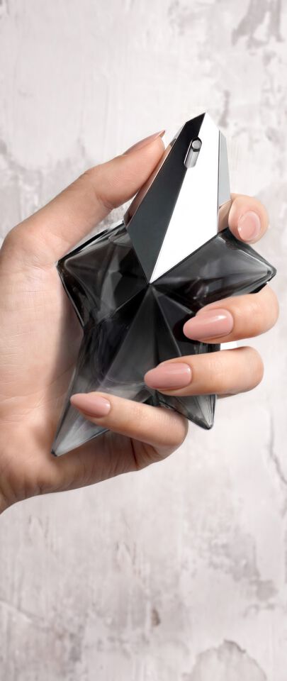 Une main feminine tenant une flacon de Mugler Angel Fantasm