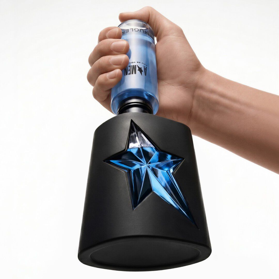 un flacon de parfum en noir avec une etoile bleue avec une main qui tient un flacon recharge