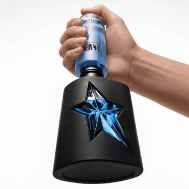 un flacon de parfum en noir avec une etoile bleue avec une main qui tient un flacon recharge