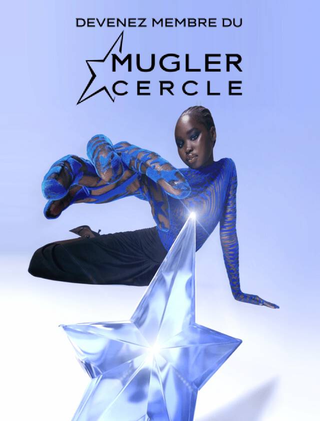 Une personne posant de maniere artistique a cote d'une etoile en cristal, portant un vetement bleu et noir avec des motifs.