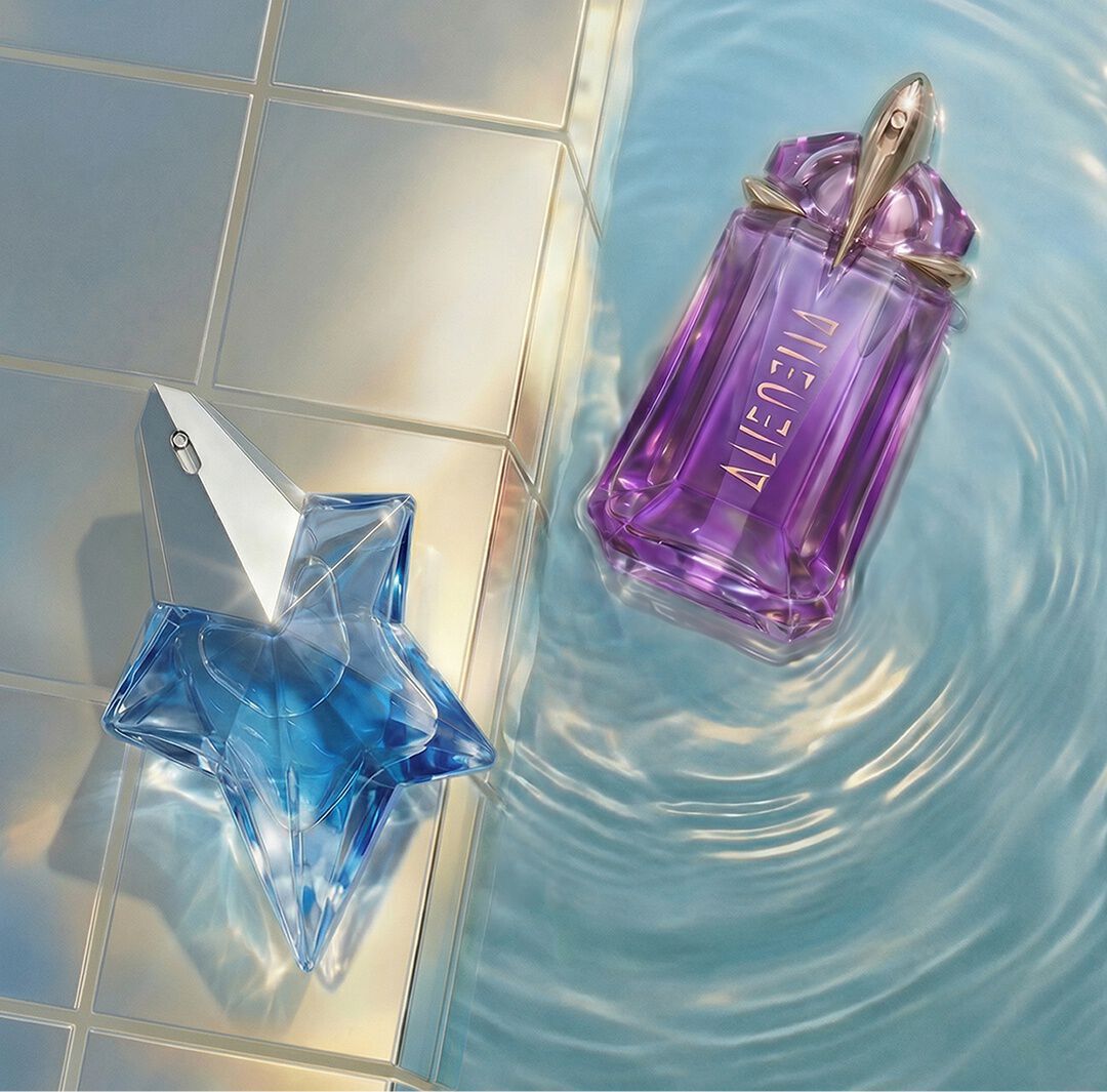 Un flacon d'eau de parfum Mugler Angel, place a cote d'un flacon violet d'eau de parfum Mugler Alien, flotte dans l'eau scintillante d'une piscine, pres de carreaux clairs.