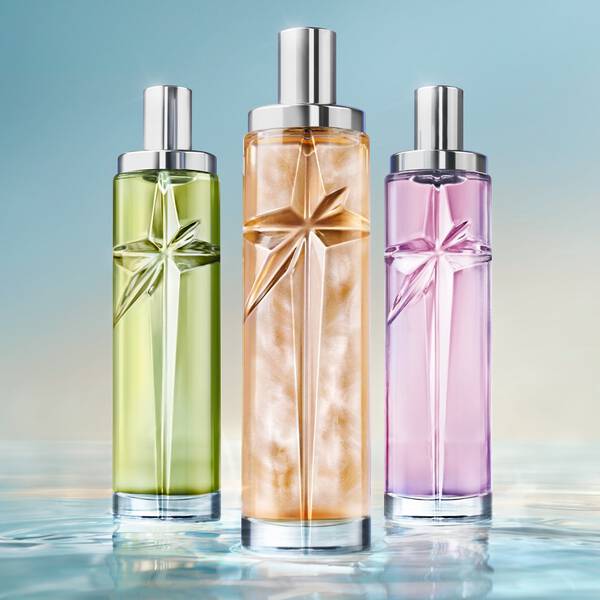trois flacons de parfums rose, vert et orange poses sur de l'eau