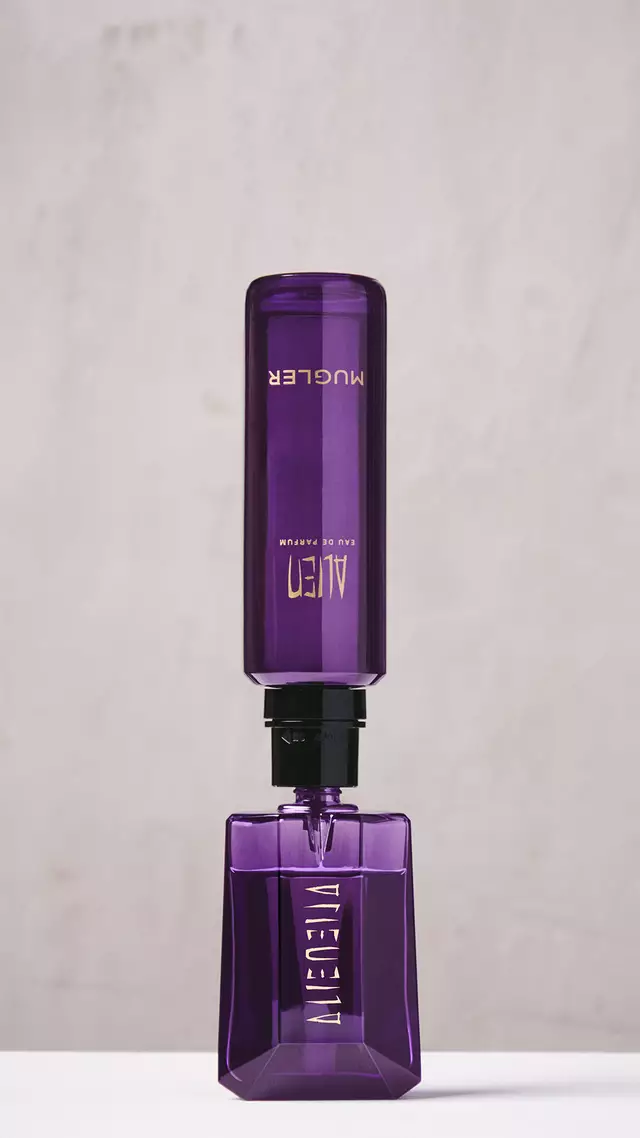 Une main en train de remplir le flacon violet de l'Eau de Parfum Alien a l'aide d'un flacon de recharge violet place a l'envers.