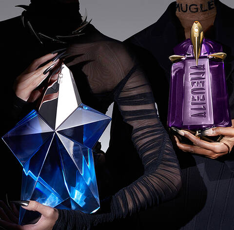 Deux silhouettes presentees en ombre, l'une tenant un flacon de parfum avec un design en cristal bleu, et l'autre tenant un flacon de parfum violet. L'arriere-plan est gris degrade.