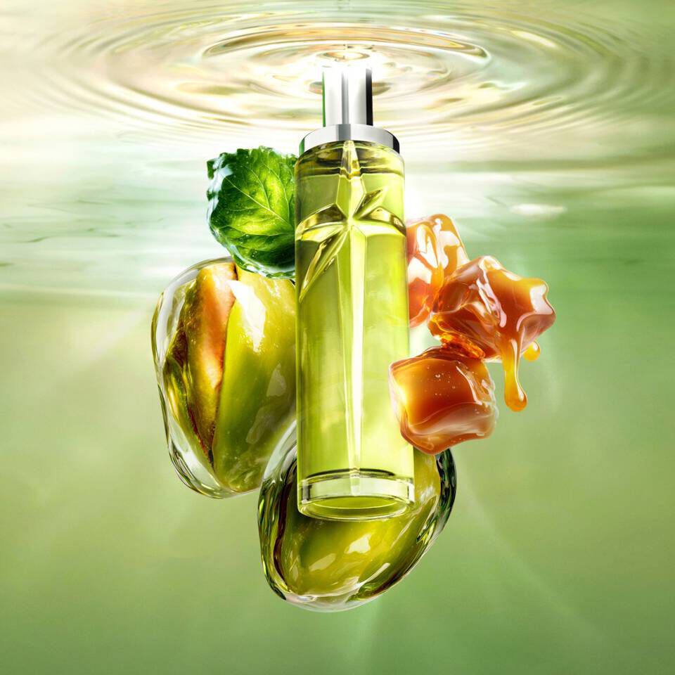 Un flacon de parfum vert en forme d'etoile flottant dans l'eau, accompagne de pistaches et de caramel.